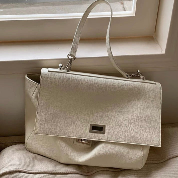 Beige handbag on a light-colored surface with a neutral background