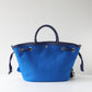 Blue tote bag with black handles and drawstring on a white background