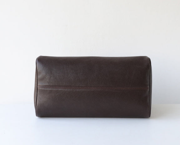 Brown leather toiletry bag on a white background